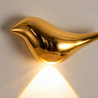 Close-up of the reflective gold bird wall light and concealed lower emitter