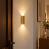 Gold cylindrical motion sensor wall light casting warm light up and down