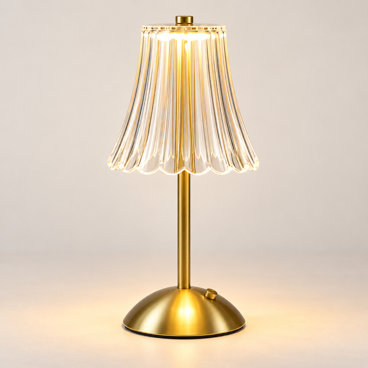 Gold rechargeable touch table lamp with clear fluted shade in a light studio