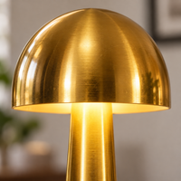Close-up of the rounded gold shade, warm underside and tapered lamp body
