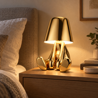 Sculptural gold seated figure lamp displayed on a living room console