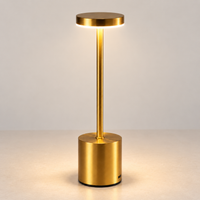 Gold rechargeable cordless touch table lamp switched on against a light interior wall