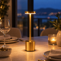 Gold cordless touch table lamp illuminating a walnut bedside table at dusk