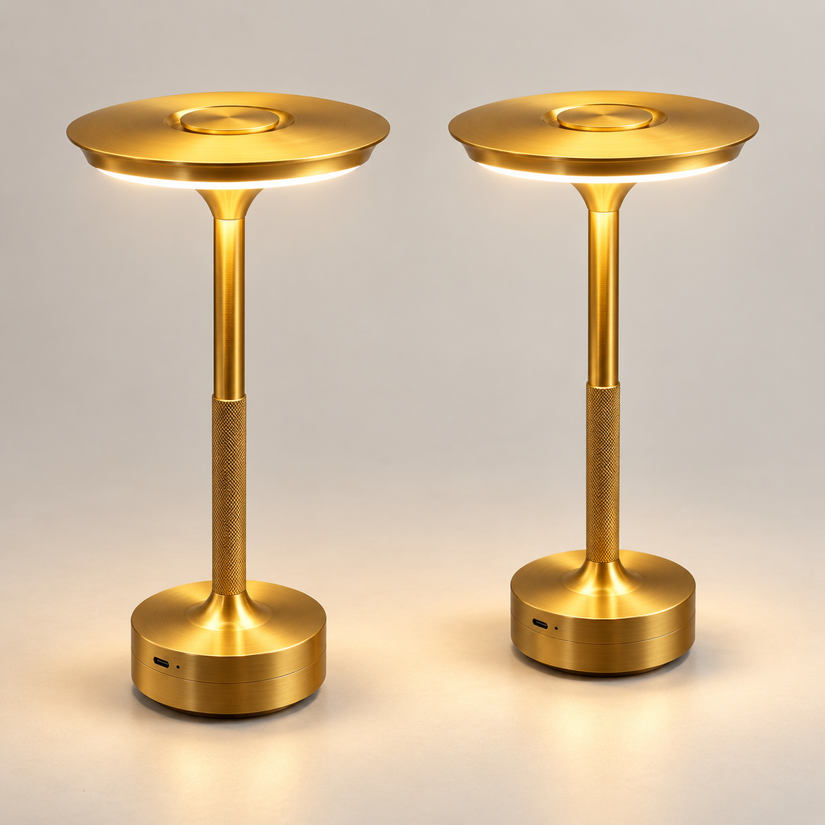 Set of two gold rechargeable touch table lamps switched on in a light studio