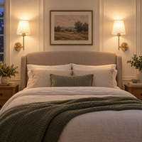 Pair of gold fabric-shade wall sconces mounted beside a neutral bed