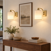 Set of two gold cordless wall sconces with linen-effect shades on a light wall