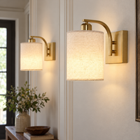 Close-up of two gold sconces showing woven shades, curved arms and backplates