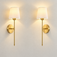 Set of two gold cordless wall sconces with linen shades switched on